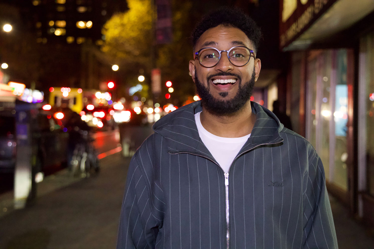 Comedian Ali Sultan smiles on a busy New York City street.